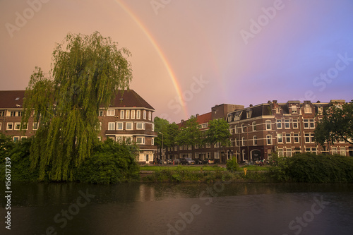 Dramatic sky with a rainbow over a canal in Amsterdam, The Netherlands