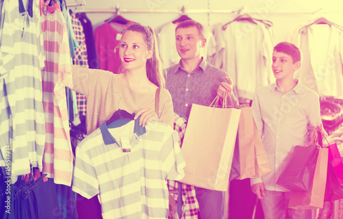 Family of three with teenager choosing clothes