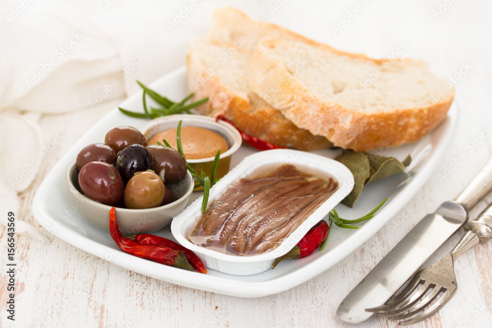 anchovies, olives, bread and fish pate on dish