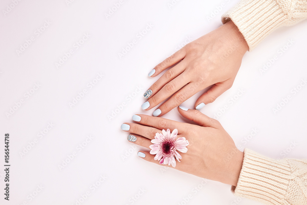 Fototapeta Kobiece dłonie z manicure i różowy kwiat.