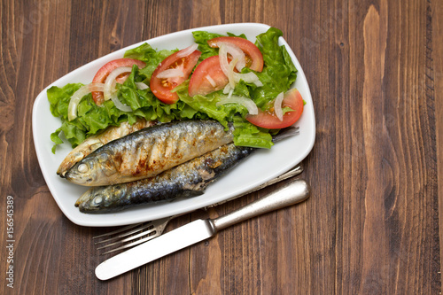 grilled sardines with salad on white dish