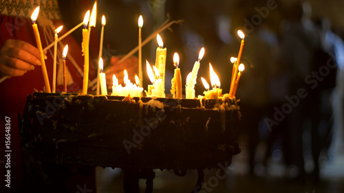 Close up of prayers hands lighting candles in the Holy Sepulchre Church in Jerusalem