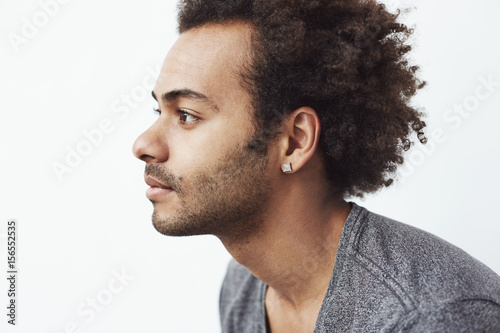 Portrait of young handsome african man in profile over white background.