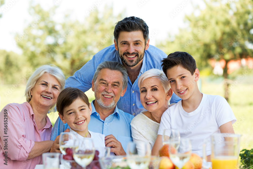Family sitting at table outdoors, smiling
Family sitting at table outdoors, smiling