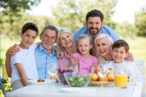 Family sitting at table outdoors  smiling  