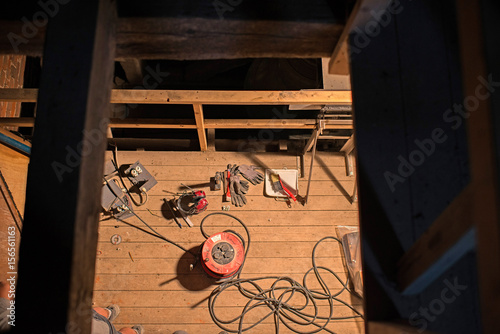 Top view of tools and electricity parts lying on wooden floor in attic of church. Restoration work.