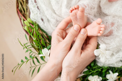 Baby feet in mother hands. Tiny Newborn Baby s feet on female Shaped hands closeup. Mom and her Child. Happy Family concept. Beautiful conceptual image of Maternity