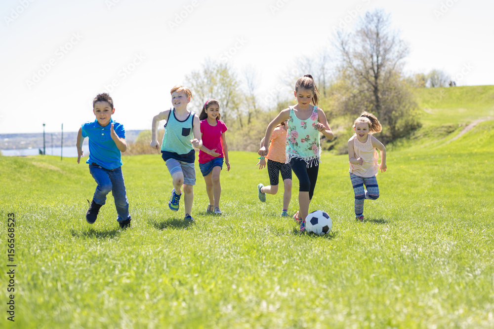 Boys and girls running towards football Boys and girls running towards football