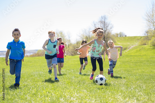 Boys and girls running towards football