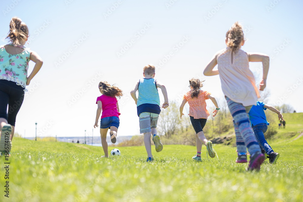 Boys and girls running towards football Boys and girls running towards football
