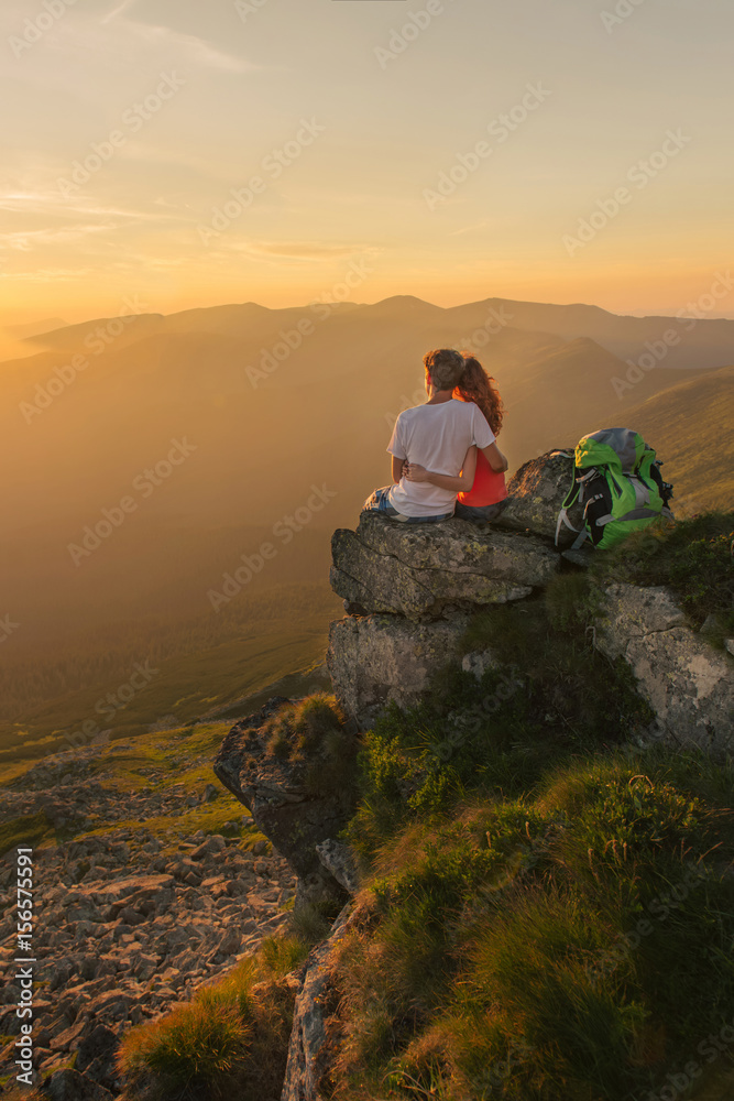 Young couple enjoy together beautiful sunset in the mountains