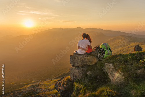 Young couple enjoy together beautiful sunset in the mountains