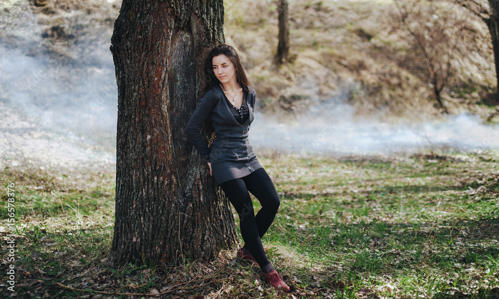 A young girl walks in the woods alone with her thoughts. Smoke over the grass. A young girl walks in the woods alone with her thoughts. Smoke over the grass.