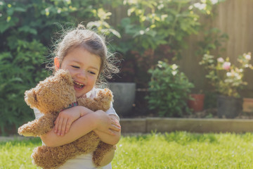 Little girl in the garden hugging her soft toy, toned photo, selective focus