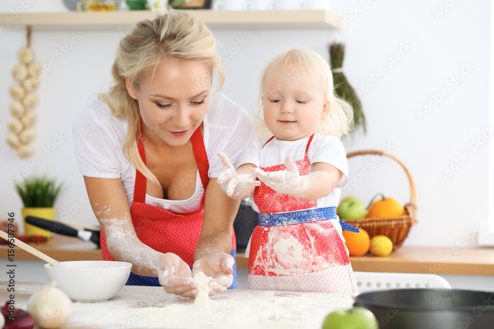 Mother and her little daughter cooking holiday pie or cookies for Mother's day. Concept of happy family in the kitchen Mother and her little daughter cooking holiday pie or cookies for Mother's day. Concept of happy family in the kitchen