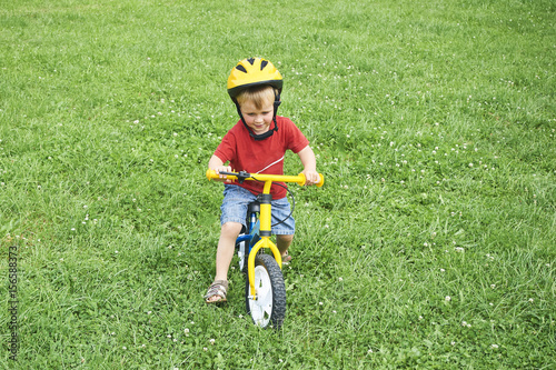 Happy toddler child boy riding bike without pedals. Kids enjoying a bicycle ride. Sport concept. Kids ride bicycle. First bike for little children. Active toddler kid playing and cycling outdoors.