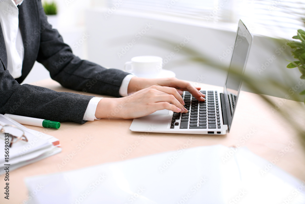 Fototapeta premium Close up of business woman hands typing on laptop computer in the white colored office