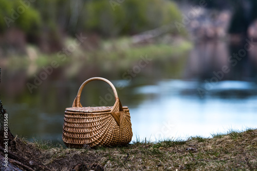 wooden woven basket in front of forest river