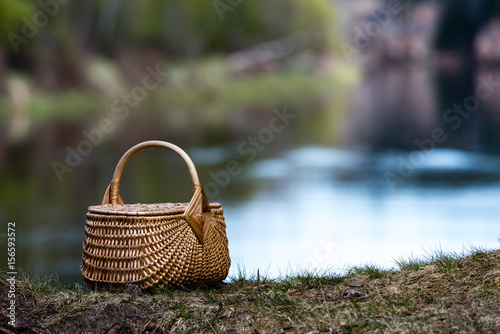 wooden woven basket in front of forest river