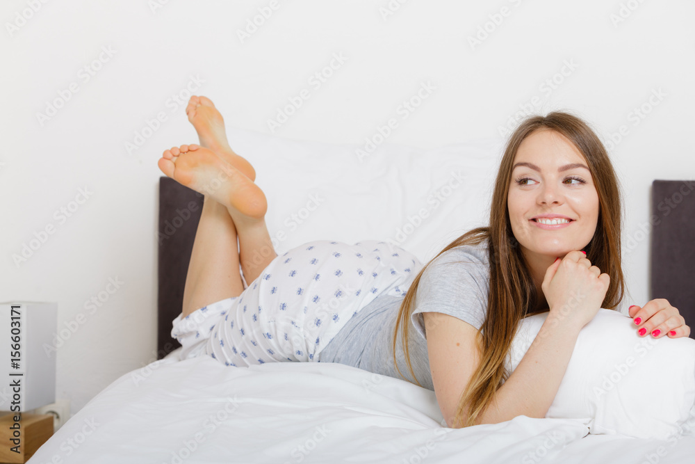 Cheerful girl rolling in bed.