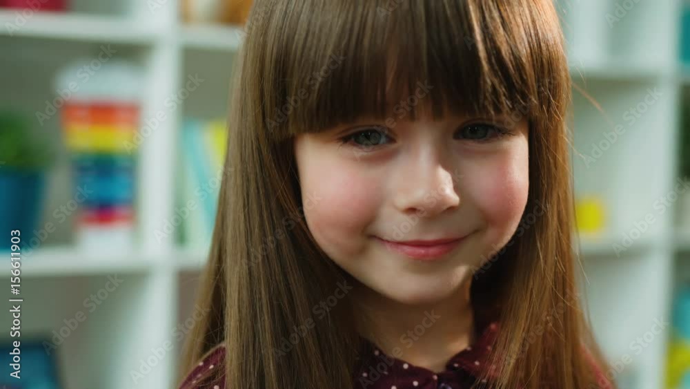 Face portrait of cute little girl looking at the camera and smiling. Kids room background. Close up Face portrait of cute little girl looking at the camera and smiling. Kids room background. Close up