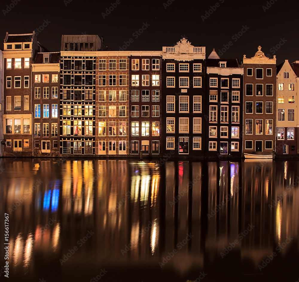 Beautiful traditional old buildings at night with reflection in Amsterdam, the Netherlands