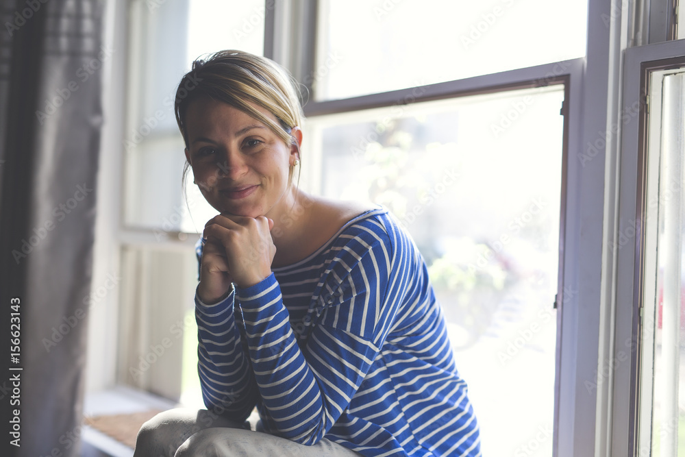 Beautiful young woman sitting near window Beautiful young woman sitting near window