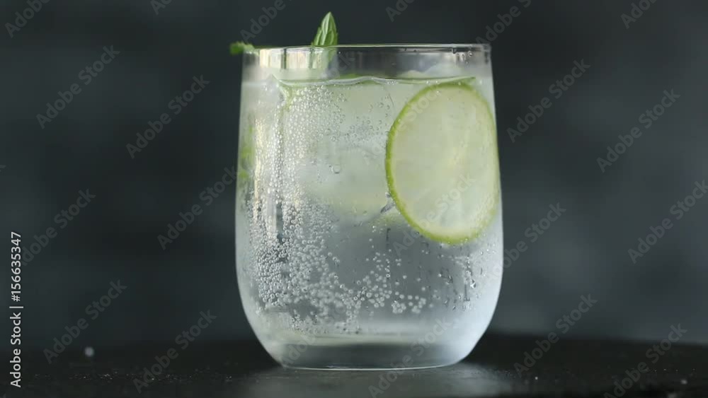 Mineral water in the glass with ice cubes,mint, lime and lemon slices on black background