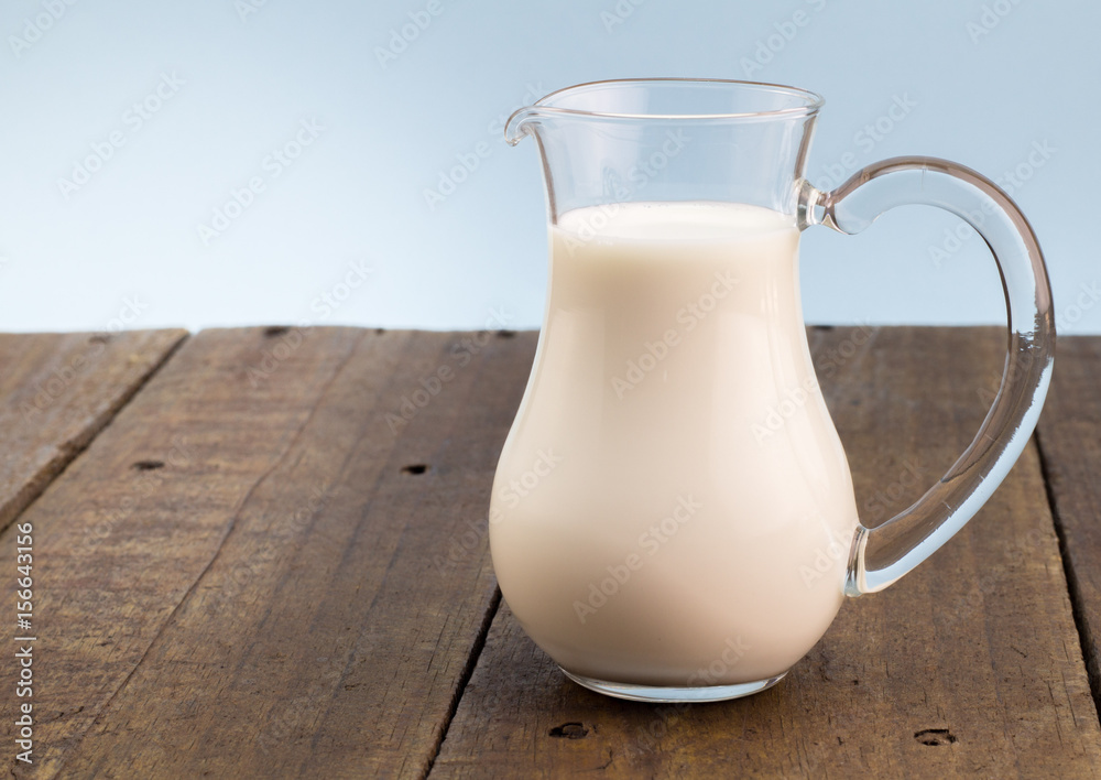 Fresh whole milk in glass jug on rough wooden table background Fresh whole milk in glass jug on rough wooden table background