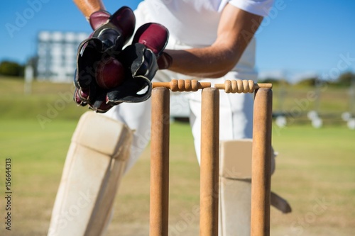Cropped image of wicket keeper standing by stumps photo