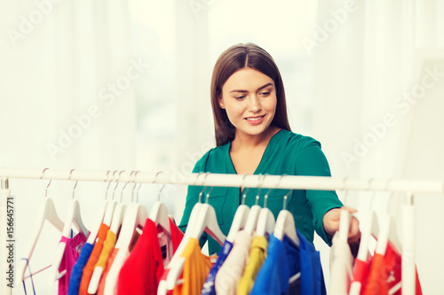 happy woman choosing clothes at home wardrobe