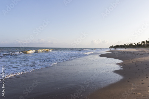 sunset on the beach with calm blue sea and waves with white foam