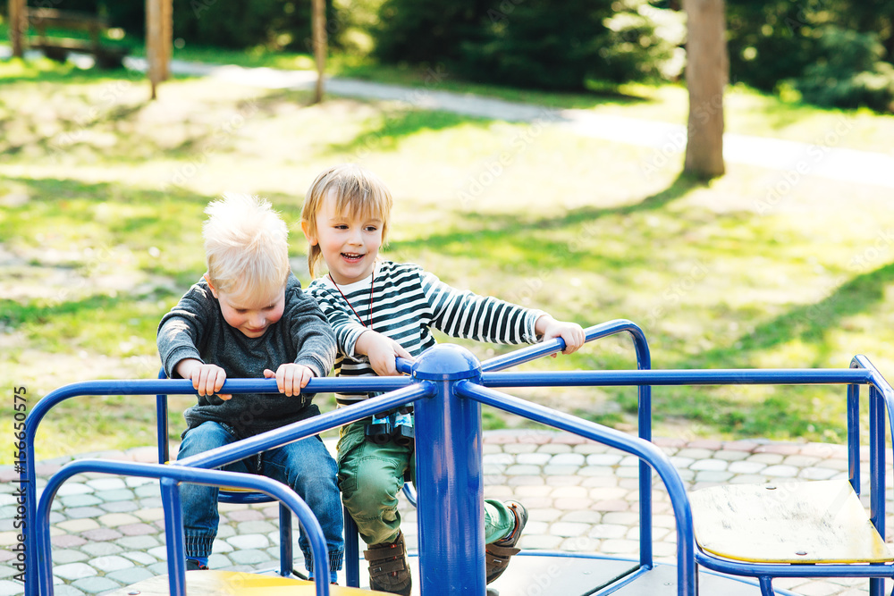 Fototapeta premium Two happy boys playing on playground in a park.