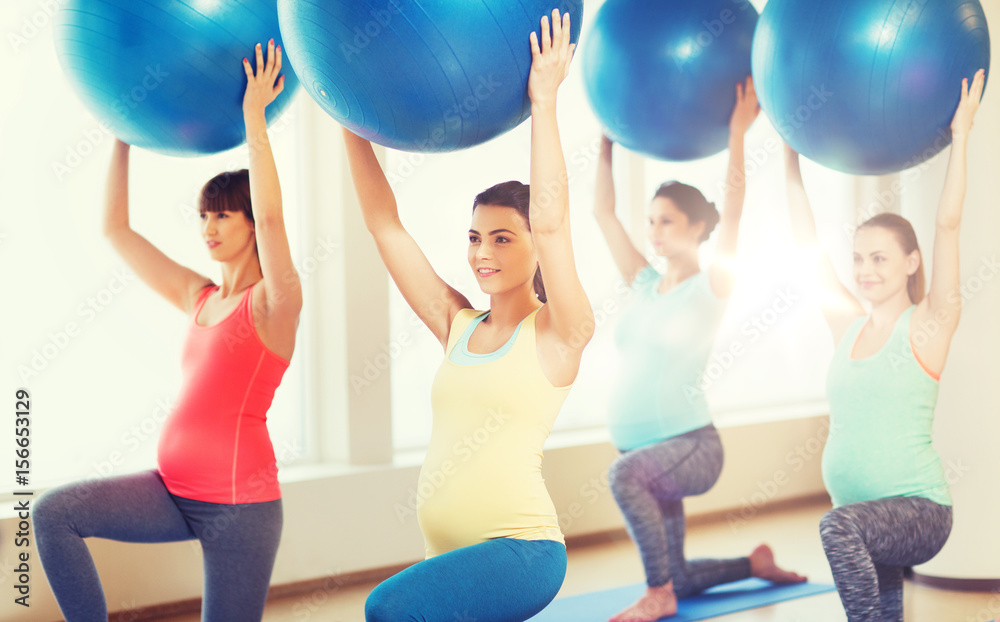 happy pregnant women exercising with ball in gym happy pregnant women exercising with ball in gym