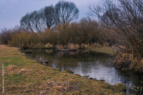 Small river among fields in early spring