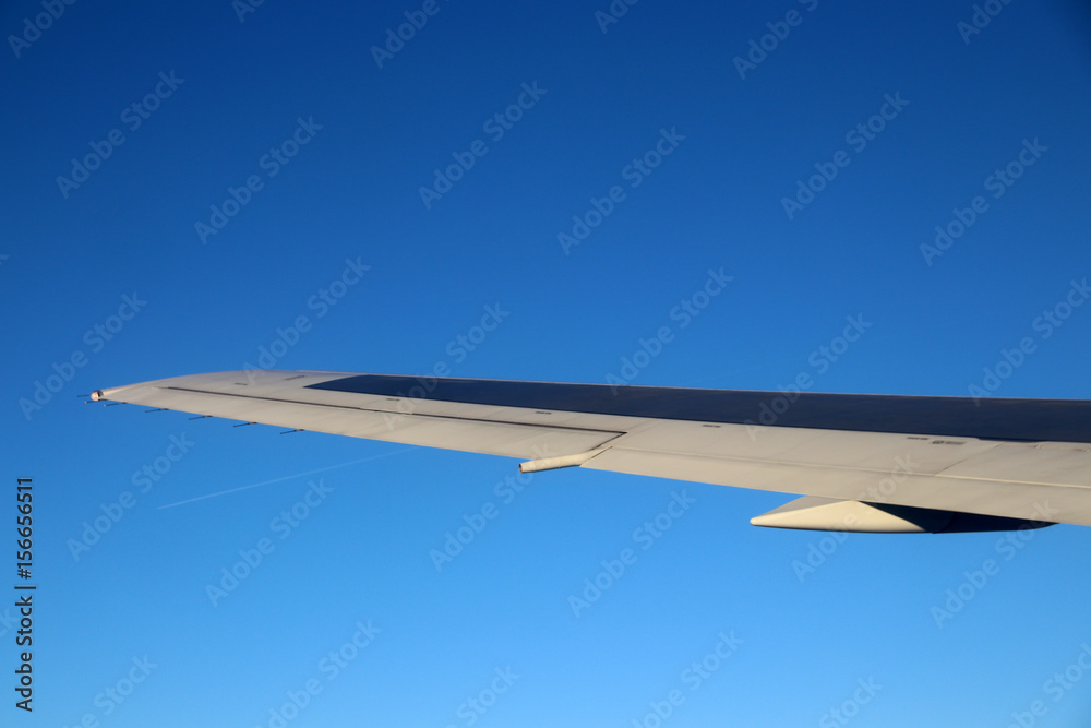 Passenger aircraft wing in flight against a blue sly Passenger aircraft wing in flight against a blue sly