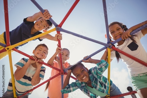 Portrait of happy schoolkids looking through dome climber photo