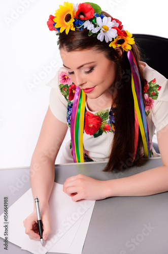 Happy businesswoman with note and pen by a desk.In the Ukrainian national costume