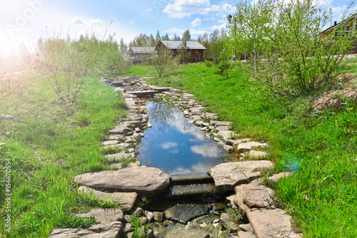 a small stream and wooden houses in the background