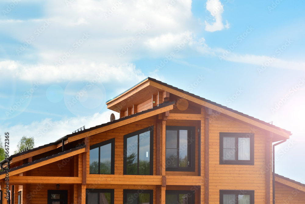 Part of the facade of a wooden house with windows and sun rays