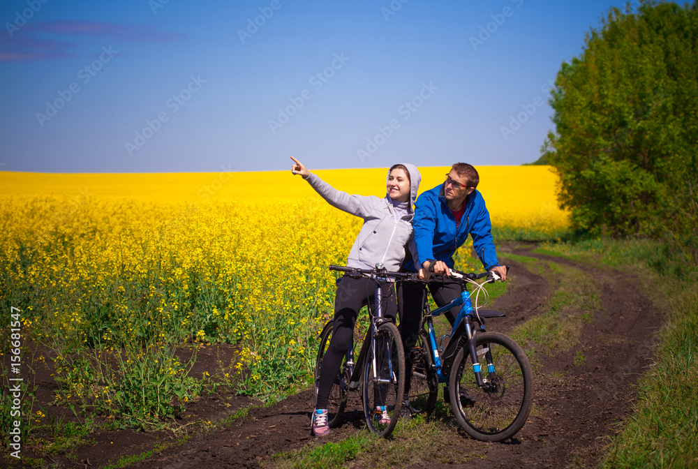 Fototapeta premium Young couple rides in rapeseed field