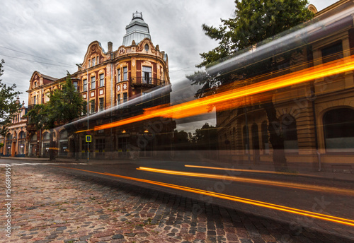 Fototapeta Naklejka Na Ścianę i Meble -  Long-exposure of bus passing by historical building.
