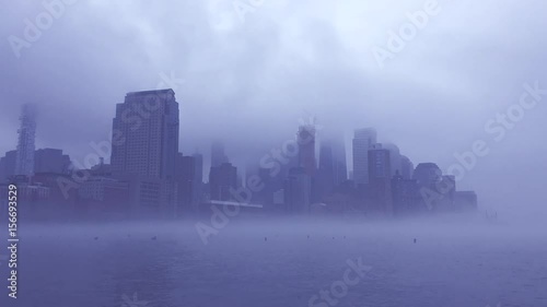 Dramatic foggy weather taking over the dark city skyline of Downtown Manhattan, New York City, in a time lapse view from the Hudson River