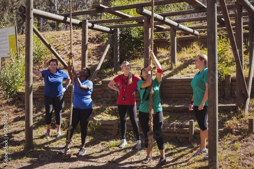 Female trainer instructing women in climbing a rope 