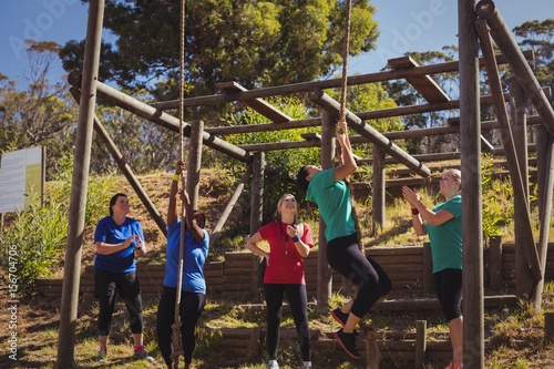 Female trainer instructing women to climb a rope 