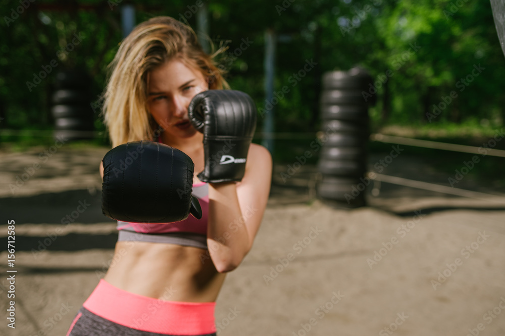 Confident girl training boxe in a open public gym, dramatic light