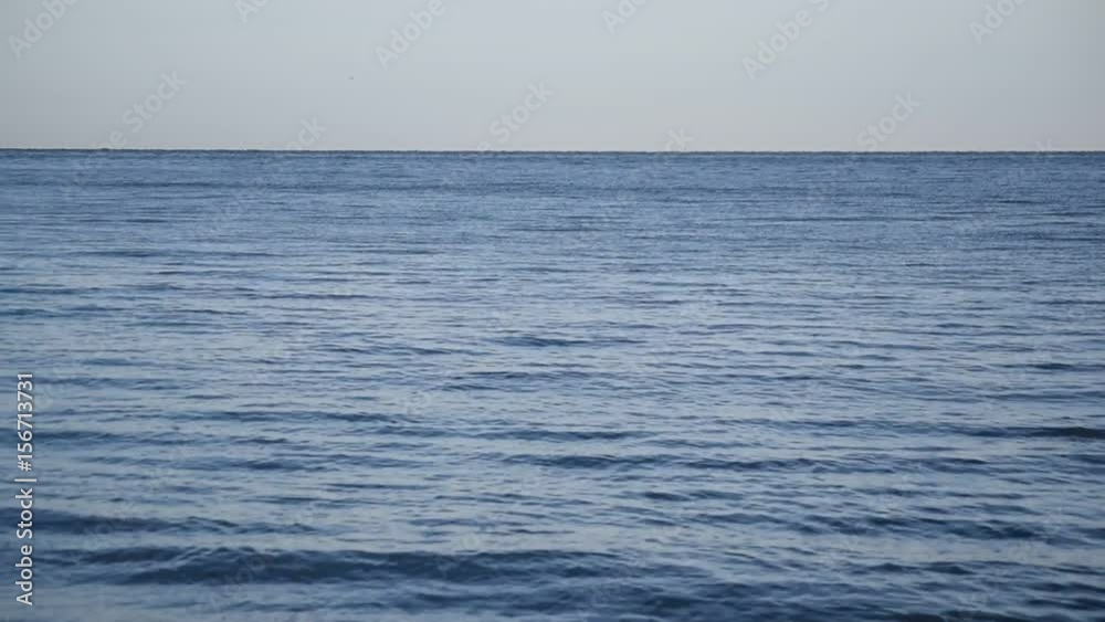 Calm blue sea or ocean with small waves and blue sky on horizon