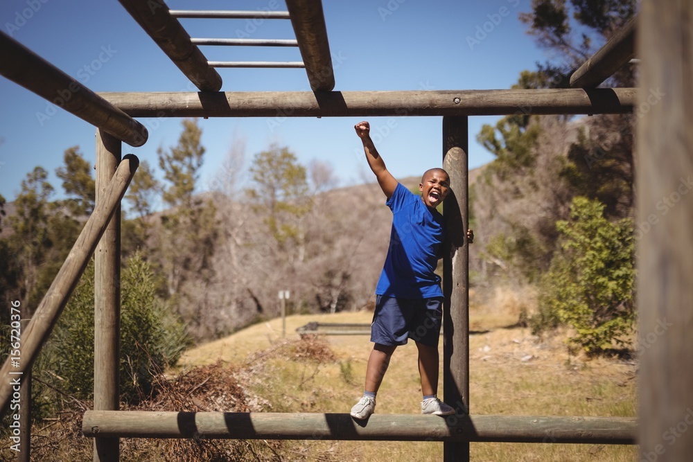 Happy boy cheering on monkey bar during obstacle course Happy boy cheering on monkey bar during obstacle course