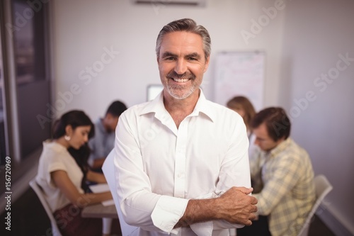 Mature businessman standing with colleagues in background