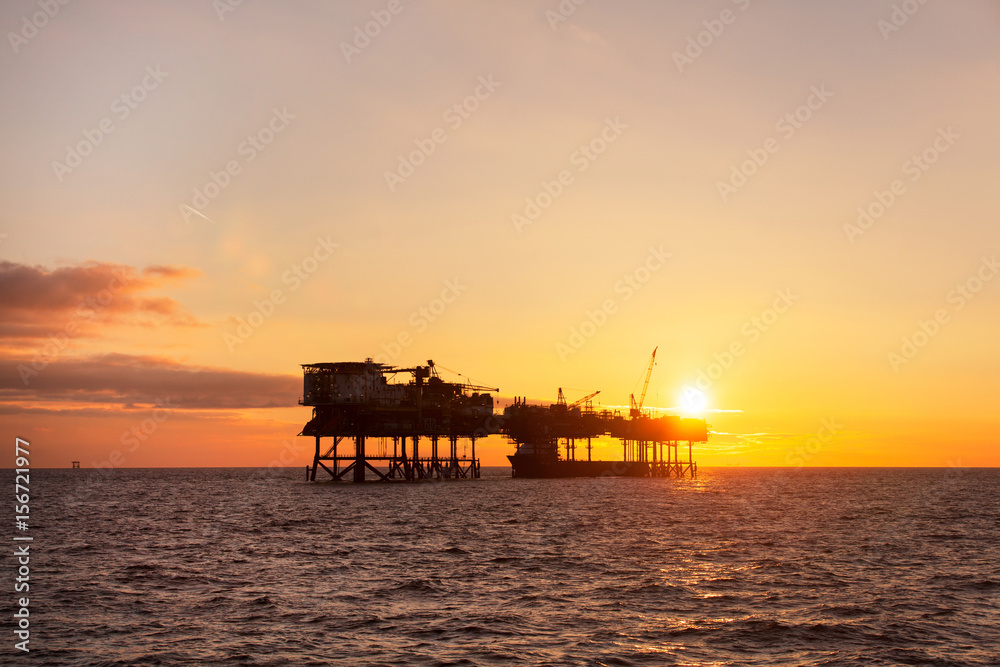An offshore oil installation and a platform supply ship at sunset time